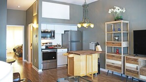 A modern kitchen with stainless steel appliances, a wooden island, and a chandelier.