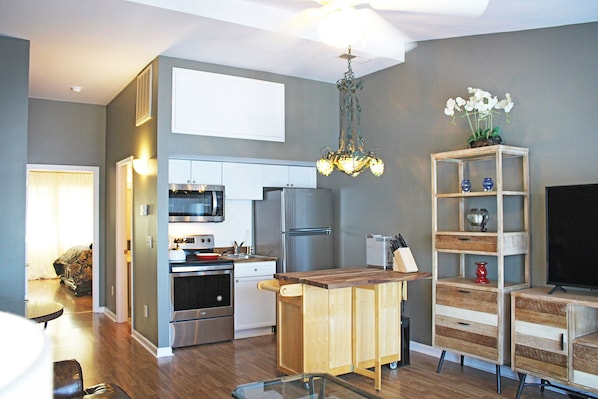 A modern kitchen with stainless steel appliances, a wooden island, and a chandelier.