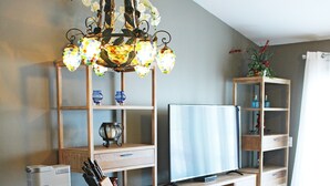 A kitchen with wooden cabinets, a built-in island, a chandelier, a television, and a bookshelf.