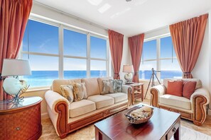 Un salon spacieux doté d’une grande fenêtre donnant sur la mer, de deux canapés, d’une table basse et d’une lampe.