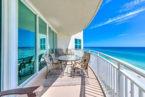 Ein Balkon mit rundem Tisch und Stühlen mit Blick auf einen Strand.