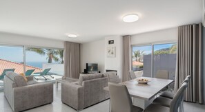 Relax in this stylish living room with a large dining table, comfortable sofa, and flat-screen TV.