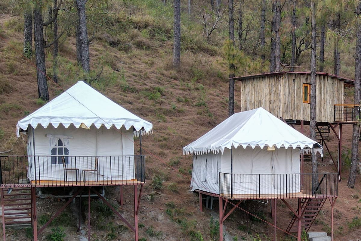 Two white tents with metal railings, one with a window and a door, and the other with a staircase.