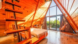 A cozy, wooden interior with a loft bed, a dining table, and a large window offering a view of the outdoors. - Paradise Pool Resort (Nainital)