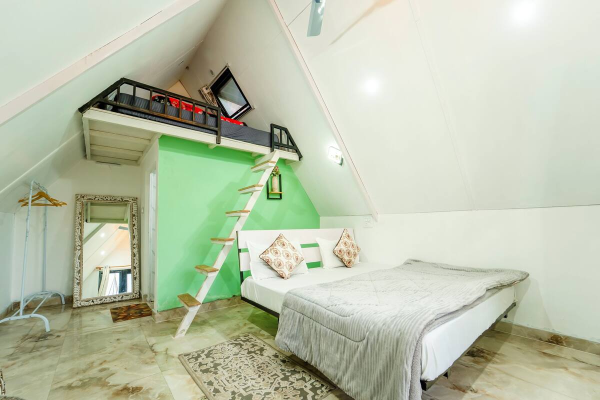 A bedroom with a bunk bed, a green accent wall, a large mirror, and a patterned rug.
