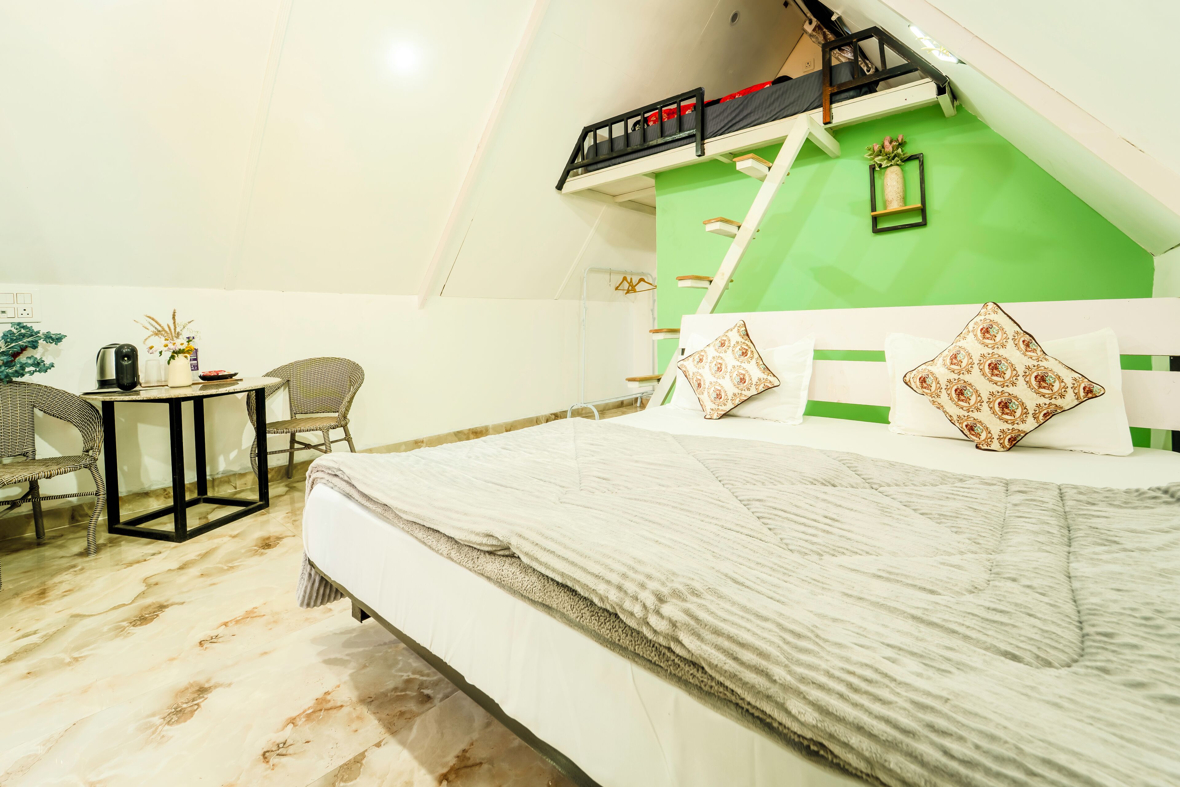A bedroom with a bunk bed, a small table with a kettle, and wicker chairs.