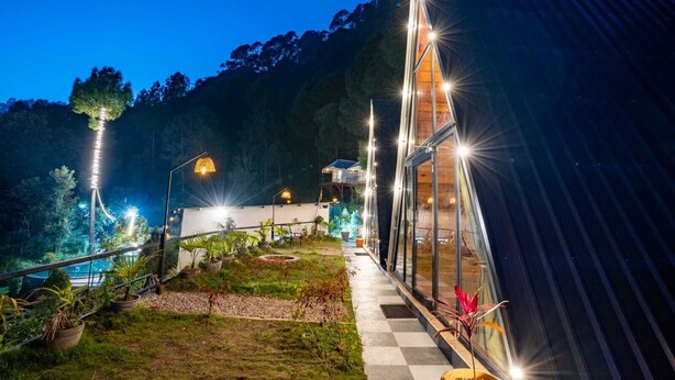 A modern building with a glass facade, surrounded by a landscaped garden with a pathway leading to the entrance. - Paradise Pool Resort (Nainital)