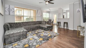 A modern living room with a sectional sofa, a ceiling fan, and a patterned rug.