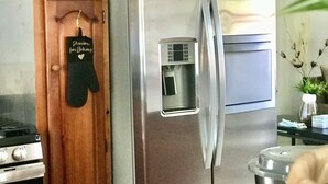 A stainless steel refrigerator with a water dispenser, a stove, and wooden cabinets.