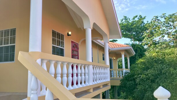 A multi-story building with a beige exterior, white balustrades, and a red door.