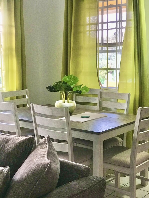 A dining area with a table, chairs, and a plant.