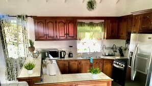 A kitchen with wooden cabinets, a central island, stainless steel appliances, and a dining area with a table and chairs.