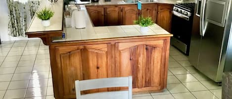 Geladeira, mesas de jantar, cozinha com ilha