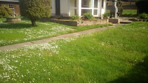 A house with a front yard, a pathway, and a garden area with white flowers. - Quiet vacation home with garden (Lichtenstein/Sa.)
