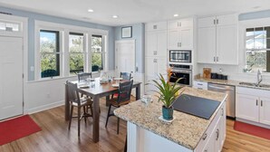 A modern kitchen with white cabinets, a granite countertop, and a central island. - Canalfront Dog Friendly Home in Frisco with Elevator and Private Boat Dock (Frisco)