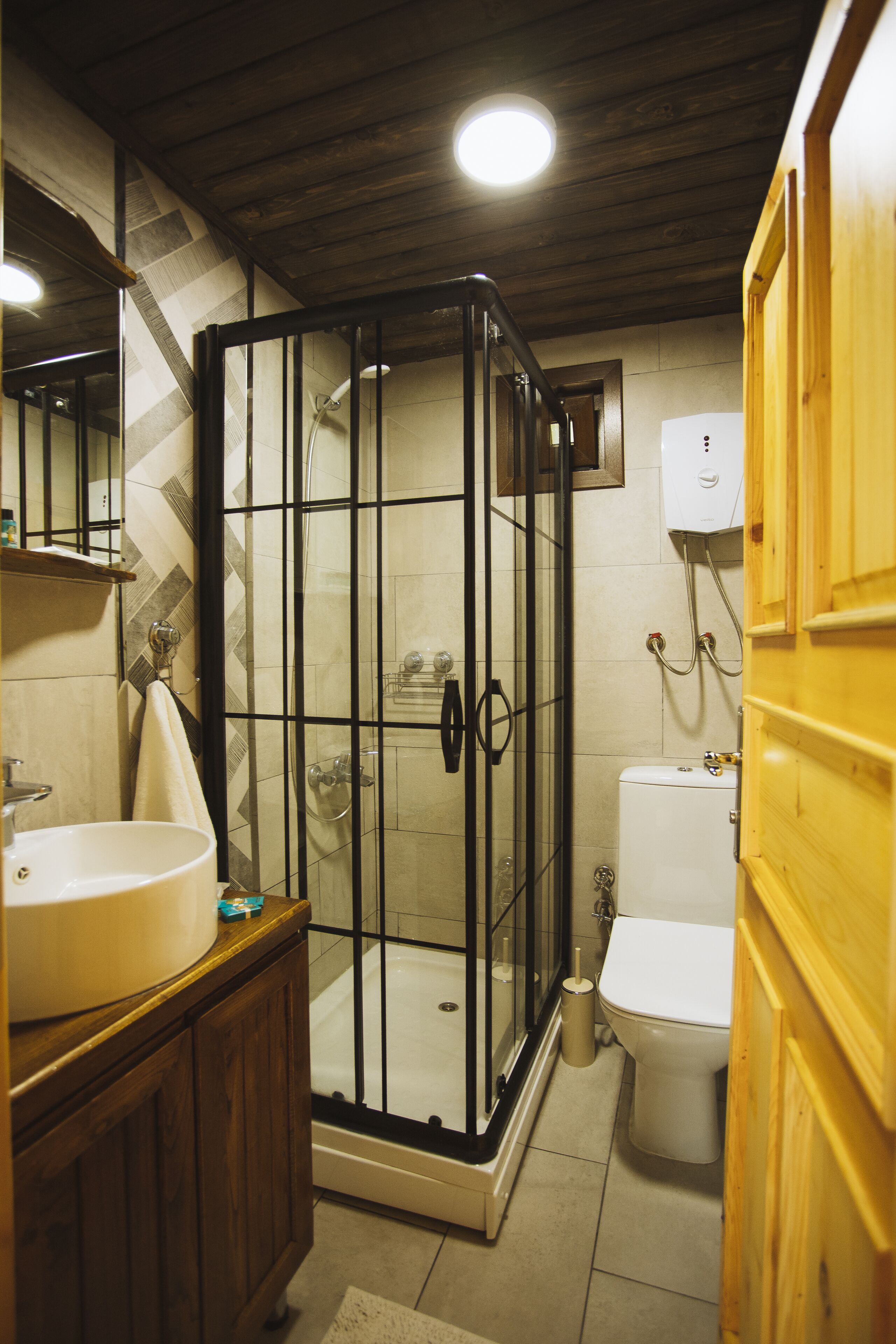 Ein Badezimmer mit Duschkabine, Waschbecken, Toilette und Holzschränken.