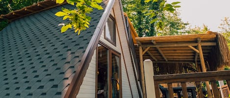 A modern house with a unique triangular roof, a wooden deck, and a covered outdoor area.