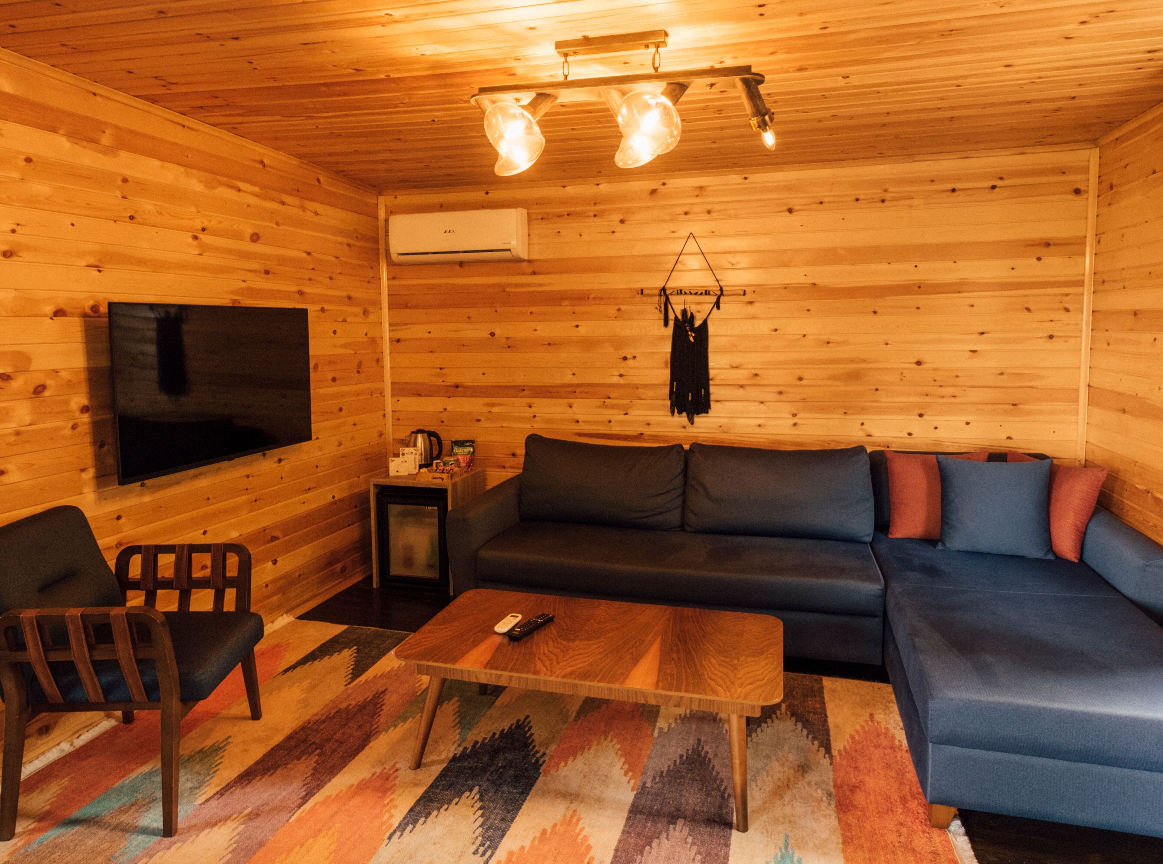 A cozy cabin interior with a wooden interior, a sofa, a television, and a coffee table.