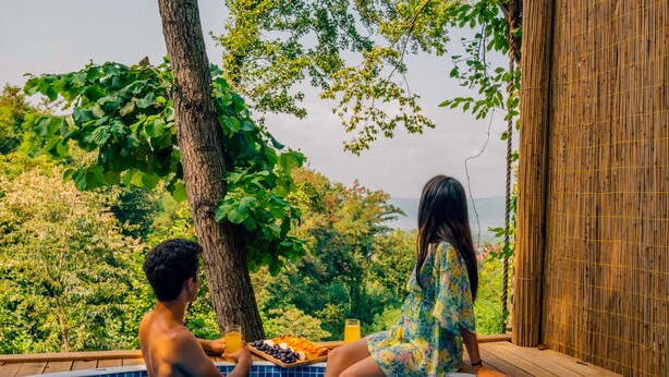 Un couple dans une piscine, avec vue sur la verdure et une clôture en bambou.