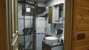 A wooden cabin bathroom with a glass shower enclosure, a sink, and a toilet.