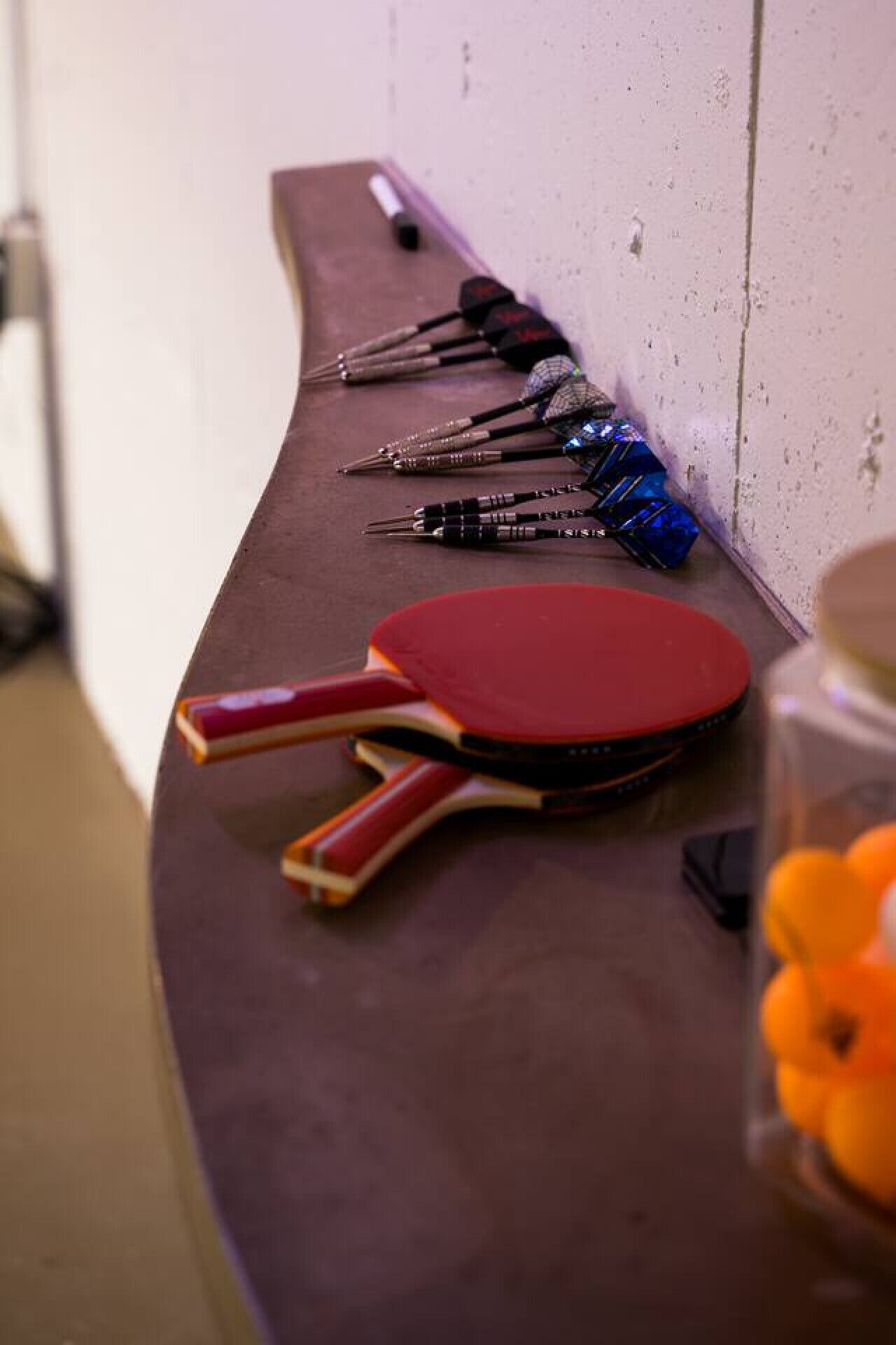 A curved counter with a red paddle, several pens, and a jar of oranges.