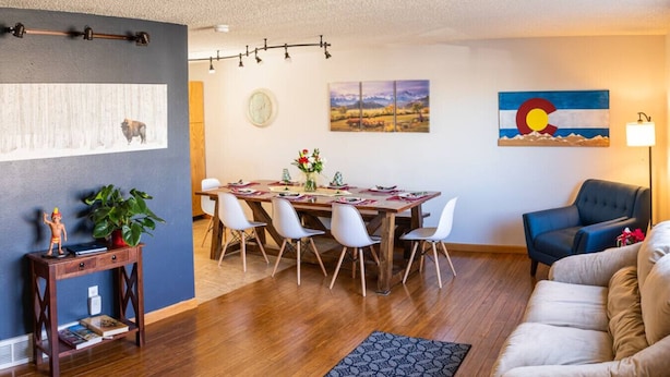 Ein Wohnzimmer mit einem Holzesstisch, weißen Stühlen, einem blauen Sofa und einem Teppich.