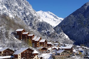 Ein Bergresort mit Chalet-ähnlichen Unterkünften, einer Seilbahn und schneebedeckten Bergen.