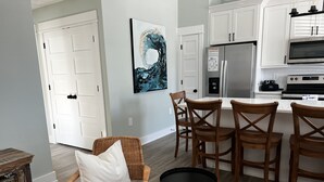 A modern kitchen with white cabinets, stainless steel appliances, and a dining area with wooden chairs and a small table.