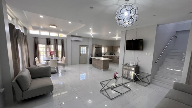 A modern living room with a sofa, coffee table, and dining area. - Gulfview Townhouse With Pool and Jacuzzi (Diego Martin)