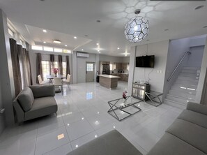 A modern living room with a sofa, coffee table, and dining area.