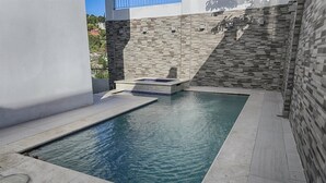 A rectangular pool with a tiled edge, surrounded by a stone wall and a white wall. - Gulfview Townhouse With Pool and Jacuzzi (Diego Martin)