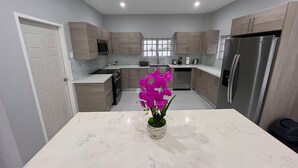 Una cocina moderna con armarios de madera clara, electrodomésticos de acero inoxidable y encimera de mármol.