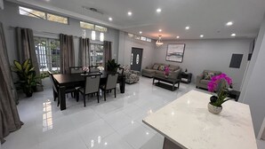 Una sala de estar moderna con comedor, que incluye un sofá, una mesa de centro y una mesa de comedor con sillas.