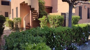 A building with a spiral staircase leading to an upper level, surrounded by well-maintained hedges and a tree. - L'équinoxe - Charmant logement 150m de la plage (Leucate)