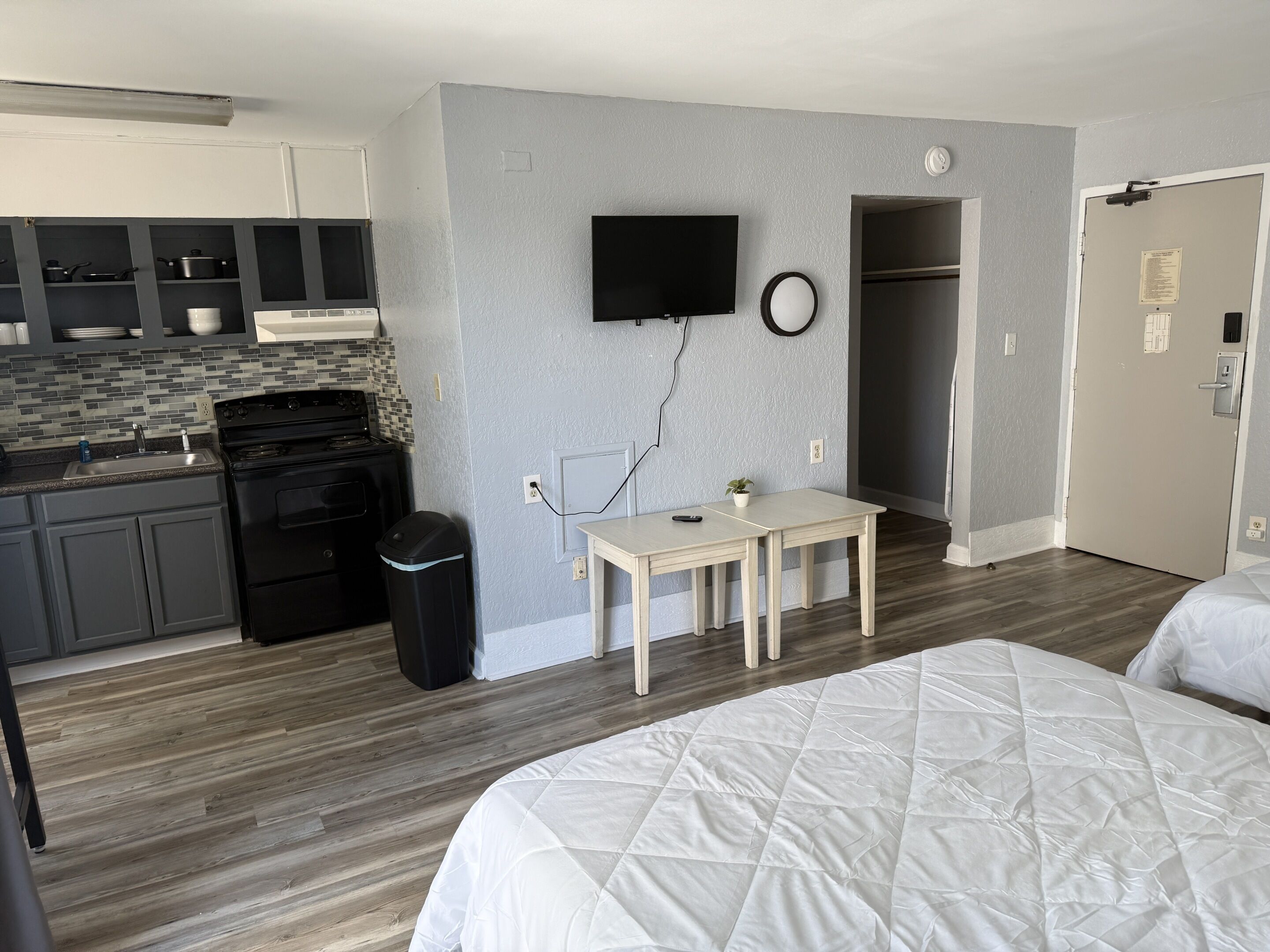Ein Hotelzimmer mit einer Küchenzeile, einem Fernseher, einem Nachttisch und einem Bett.
