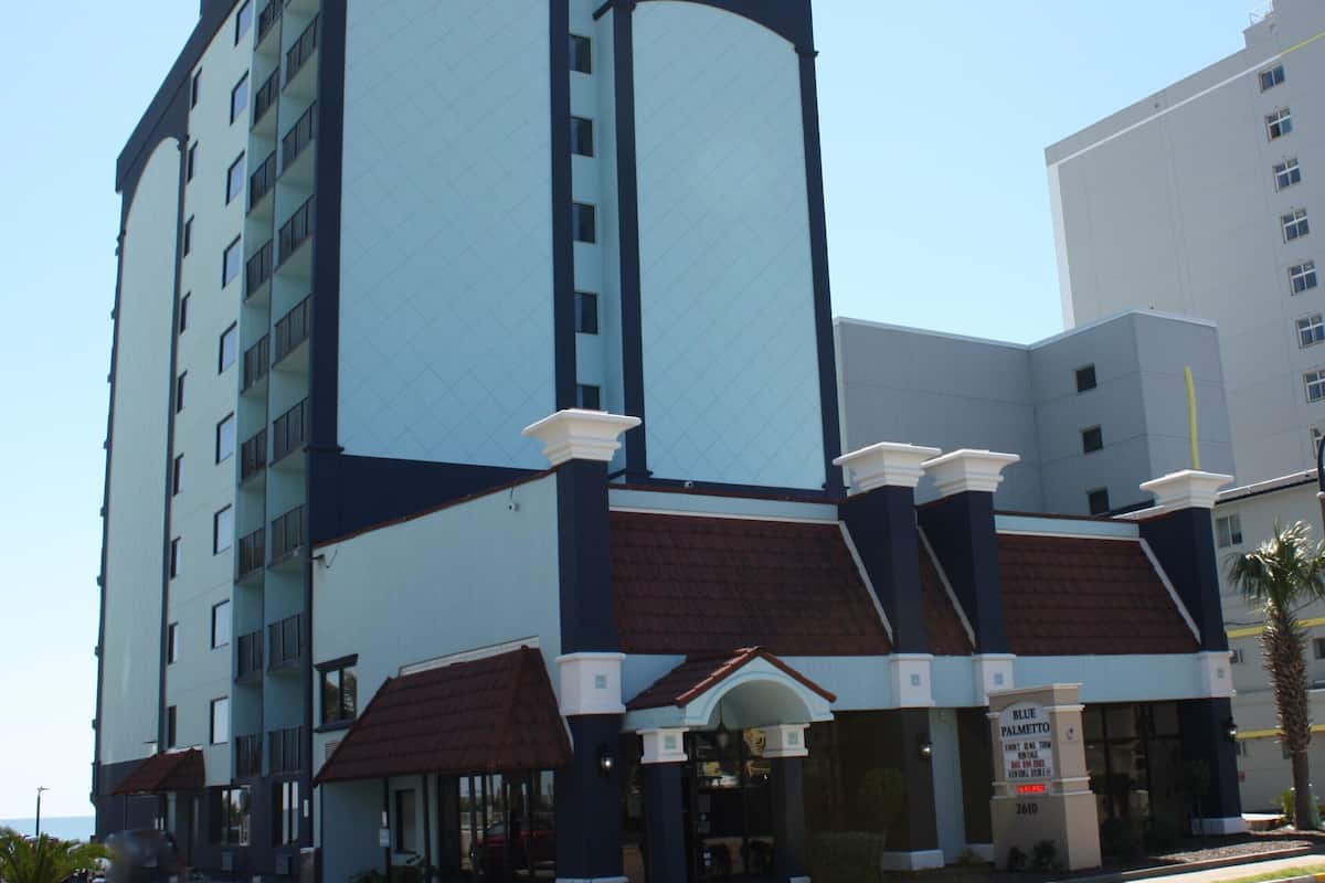A multi-story hotel with a modern design, featuring a prominent entrance with a covered area and a signboard.