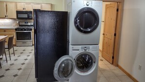 A compact kitchen with a refrigerator, microwave, stove, and a stacked washer and dryer. - Very quiet ground floor basement apartment in the country, big outdoor space,!!! (THAYNE, WY)