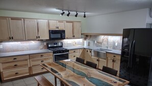 A modern kitchen with wooden cabinets, a black refrigerator, a built-in microwave, and a dining table with chairs. - Very quiet ground floor basement apartment in the country, big outdoor space,!!! (THAYNE, WY)