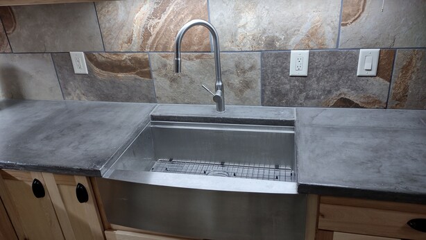 A kitchen with a stainless steel sink, wooden cabinets, and a stone backsplash. - Very quiet ground floor basement apartment in the country, big outdoor space,!!! (THAYNE, WY)