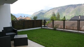 Een terras met tuinmeubilair, een gazon en uitzicht op bergen.
