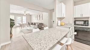 A modern kitchen with granite countertops, white cabinets, and a built-in microwave. - Bright 2BR King Suite w Gym& close to Downtown (Austin)