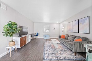 Relax in this stylish living room with a large window, flat-screen TV, and comfortable seating.