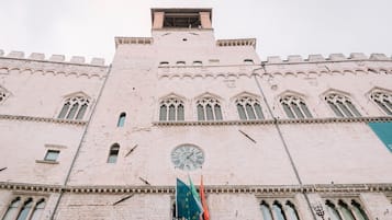 Ein großes, historisches Gebäude mit einem Glockenturm, Bogenfenstern und Fahnen.