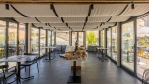 Un restaurant spacieux où les pâtisseries sont présentées de manière attrayante au centre de la salle, avec un mobilier moderne et de grandes fenêtres offrant une vue sur les environs.