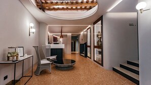 Un intérieur moderne avec une table ronde, des chaises en osier, un petit coin cuisine et un escalier menant à une terrasse.