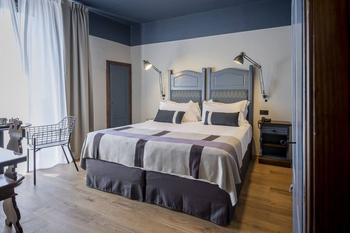 A neatly arranged bedroom with a large bed, bedside lamps, a chair, and a small table.