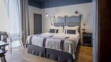 Un dormitorio ordenado con una cama grande, lámparas de noche, una silla y una mesita.