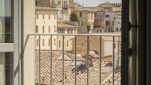 Un balcon offrant une vue sur une ville historique, avec ses toits de tuiles rouges et ses murs de pierre.