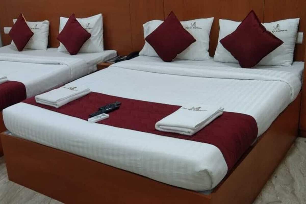 Une chambre d’hôtel avec deux lits simples, chacun recouvert d’une couverture rouge et agrémenté d’oreillers blancs.