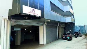 A modern building with a reflective glass facade, a sign for 'The Kit Express', and a covered parking area with motorcycles.